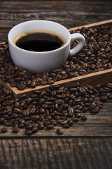 cup of coffee with beans on wooden table