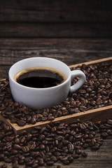 cup of coffee with beans on wooden table