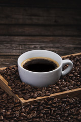 cup of coffee with beans on wooden table