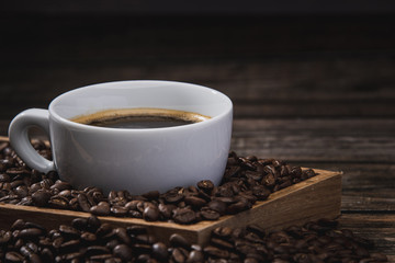 Close up cup of coffee with beans on wooden table
