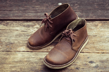 Brown stylish boots on wood background,  retro color