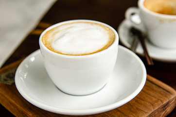 Capuchino hot coffee in white cup.