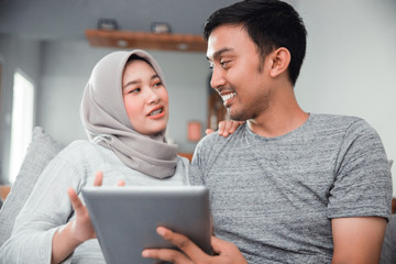 muslim pregnant woman using tablet pc with husband in livingroom
