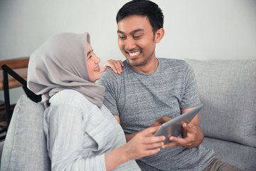 muslim pregnant woman using tablet pc with husband in livingroom