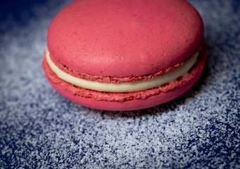 Pink Macaron or Macaroon in blue dish on wooden table. A colorful small and sweet French pastry of made of almond flour and egg whites.