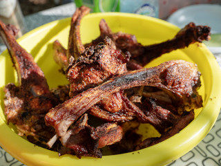 Cooked lamb ribs on the grid are in a yellow bowl on the table A picnic in the woods on a day off Hiking outdoors cooked lamb chops on the 