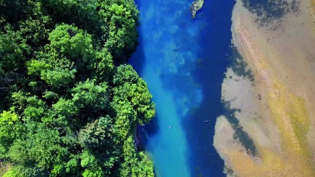Vista aerea di un lago di montagna alpino. La costa di sabbia contrasta con il blu dell'acqua e la sponda alberata. Lago del Bernigolo, Lenna, Bergamo, Italia. Valle brembana, Alpi Orobie