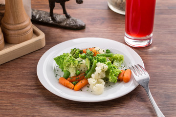 Vegetable mix with carrot, romanesco and cauliflower and berry drink on wooden table