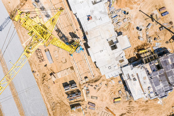 top view of high yellow tower crane standing at construction site. drone image