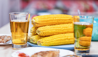 Boiled corn on the cob, roasted meat and beer in glasses