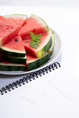 Slices of fresh watermelon with notebook paper on white marble background