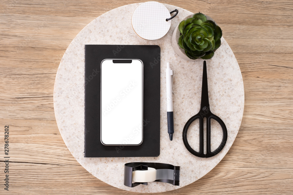 Poster mobile mock up on office desk table top view with stationery,notebook,plant on wooden table background.smart phone screen for display of design.business object flat lay.clipping path device template.