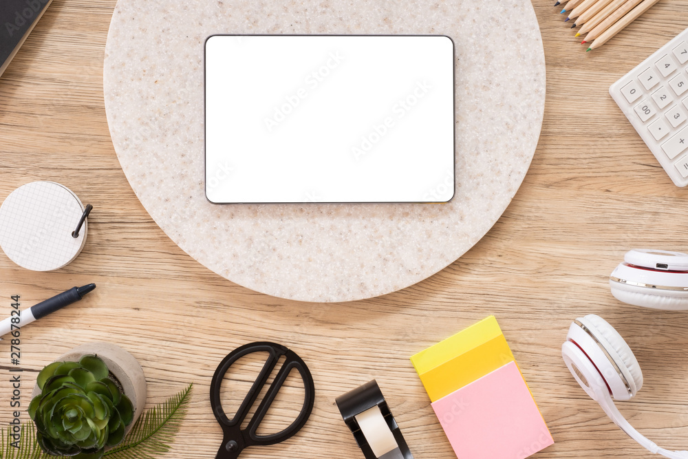 Poster tablet mock up on office desk table top view with stationery,notebook,plant on wooden table background.smart phone screen for display of design.business object flat lay.clipping path device template.