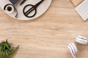 office table desk top view with stationery, notebook,headphone,plant,noteapd and caculator on wooden table 