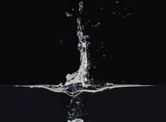 Explosion on liquid surface isolated on black background, close up view. Water bubbles after splash, rippling surface. Abstract black background for overlays design, screen blending mode layer