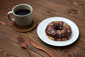 お皿にのせた チョコレート ドーナッツ とホットコーヒー 木のテーブル