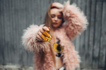 Close Up Portrait of One Stylish Girl in Pink Coat and Modern Yellow Sunglasses Posing on Street