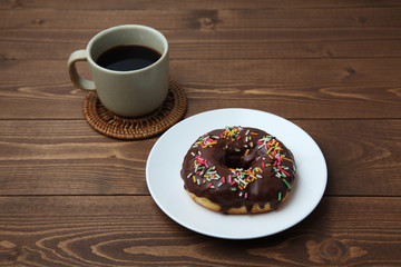 お皿にのせた チョコレート ドーナッツ とホットコーヒー 木のテーブル