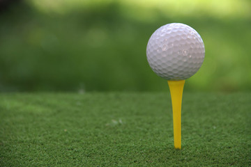 Golf ball on tee in beautiful golf course at sunset background.