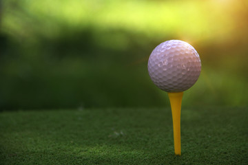 Golf ball on tee in beautiful golf course at sunset background.