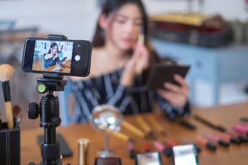 Happy girl blogger at cafe talking about makeup and beauty and recording video tutorial for internet, blogger concept