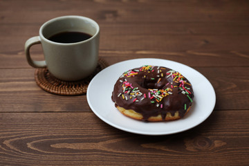 お皿にのせた チョコレート ドーナッツ とホットコーヒー 木のテーブル