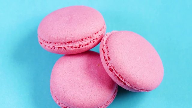 Beautiful pink cookies or macaroons are laid out on a blue bed background. Slow camera movement.