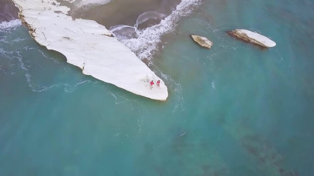 aerial view of family recreation on white stone cape in Kalymnos or Governor Beach in Cyprus, father mother and son in red shirt on sea coast, people traveling, drone camera fly around   