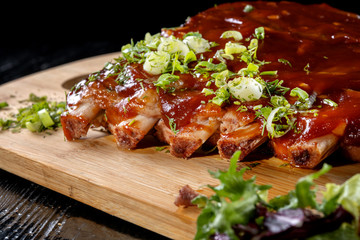 Pork ribs with sauce laid out on a wooden board.