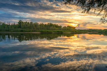 Fototapeta na wymiar Beautiful sunset nature landscape with calm river and picturesque clouds