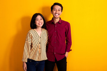 young couple standing with smile over yellow background