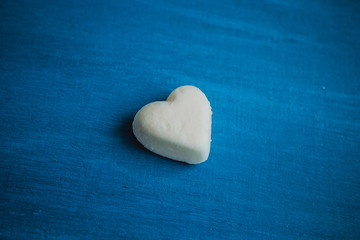 Obraz premium Heart on a blue background. White candy in the shape of a heart on a wooden background.