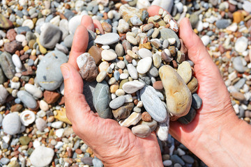 Men's tanned hands holding in the palms of beautiful sea stones on the beach