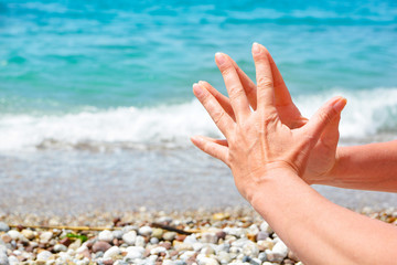 Women's tanned hands, make various gestures of the fingers on the background of the blue sea. Hindu wise 