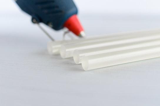 Blue Glue Gun And Hot Melt Rods On White Background