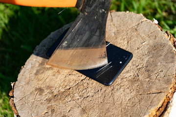 Ax cuts the phone. Destroy innovation. Vandalism act. Smartphone on the stump. Smartphone near the...