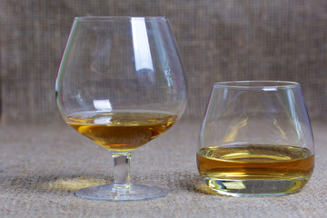 Glasses with strong alcoholic beverage poured into them. Against the backdrop of coarse linen fabric. Close-up.