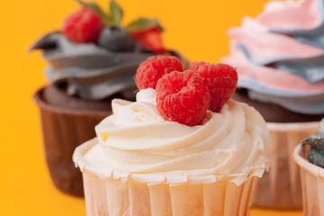 Delicious cupcakes with icing on a yellow background