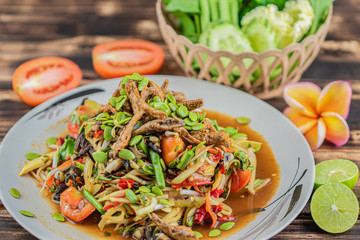 Somtum. Thai spicy green papaya salad on wooden table.(Somtum pha)