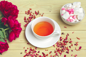 Cup of green tea on table with fresh peony flowers