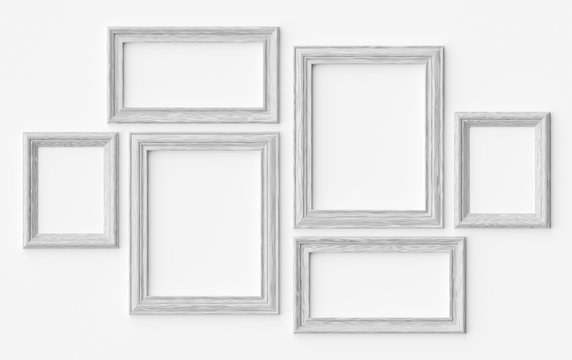 White wooden picture or photo frames on white wall with shadows