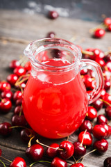 Homemade cherry drink in jug on the rustic background. Selective focus. Shallow depth of field. 