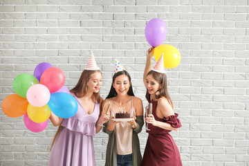 Happy women with Birthday cake near brick wall