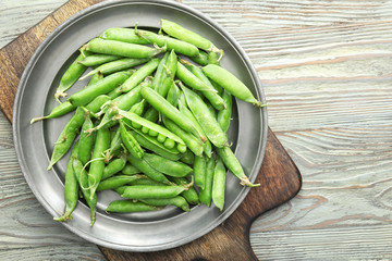 Plate with tasty fresh peas on wooden table