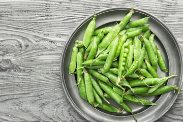 Plate with tasty fresh peas on wooden table