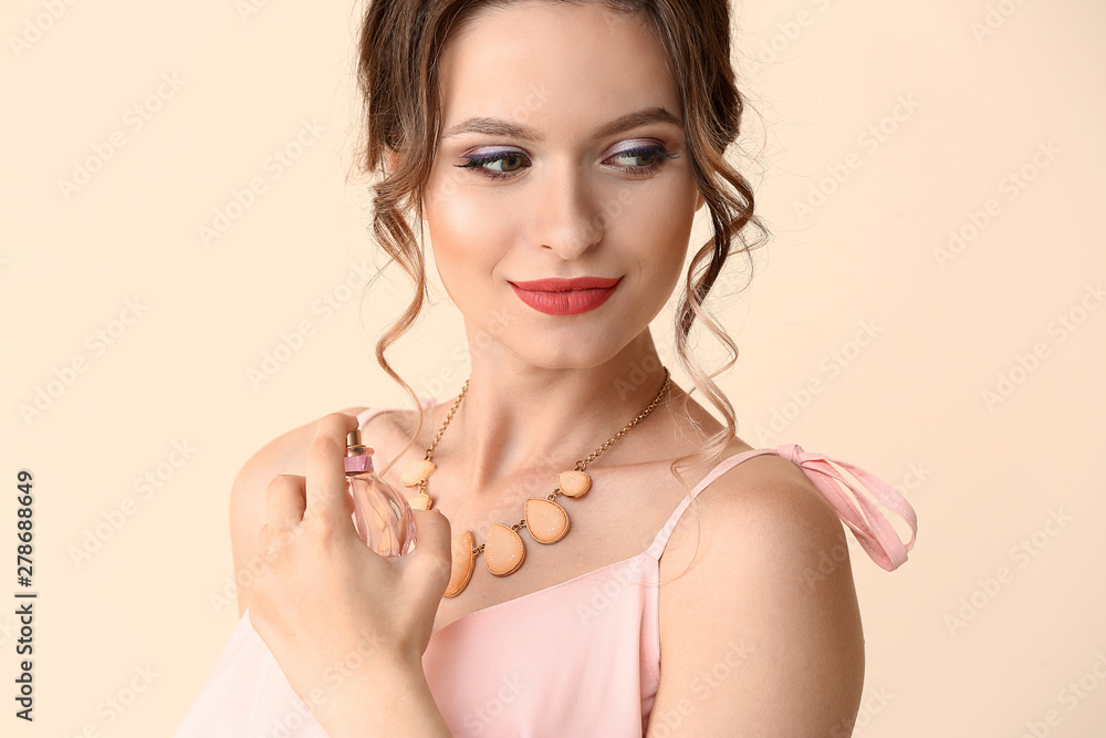 Wall mural beautiful young woman with bottle of perfume on light color background