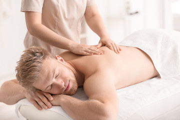Handsome young man receiving massage in spa salon
