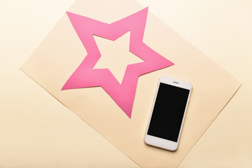 Modern mobile phone and paper star on light background