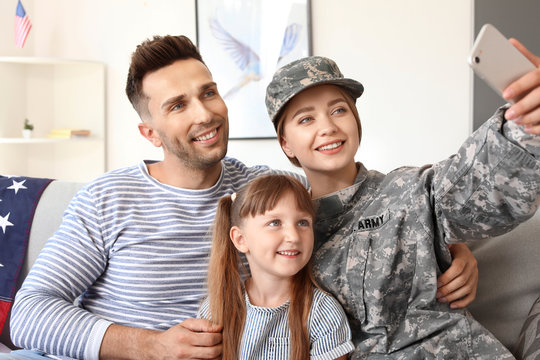 Happy female soldier taking selfie with her family at home