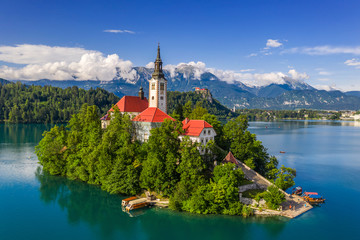 Fototapeta premium Bled, Slovenia - Aerial drone view of Lake Bled (Blejsko Jezero) with the Pilgrimage Church of the Assumption of Maria on an island and Bled Castle and Julian Alps at backgroud on a bright summer day